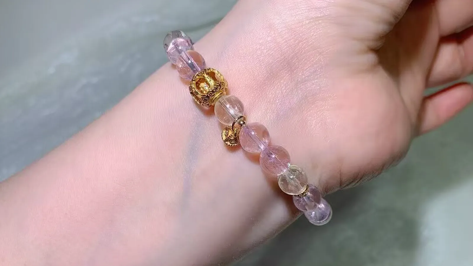 手腕上的猫眼紫锂辉手链：淡粉到淡紫的珠子，配古法饰品